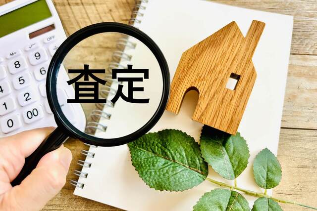 葉の上に置かれた家の模型と虫眼鏡